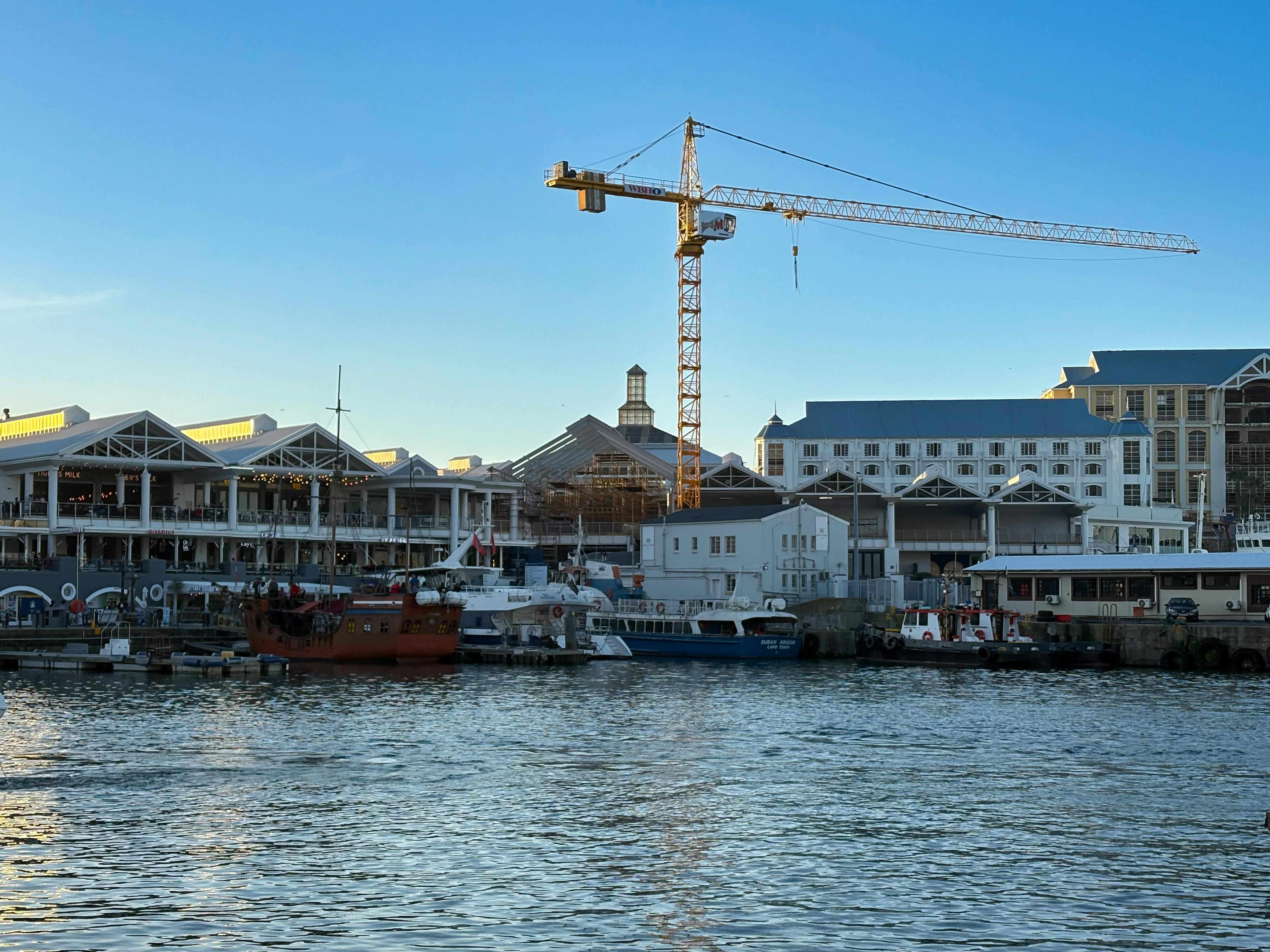 A sailing boat leaving Cape Town harbour at sunset